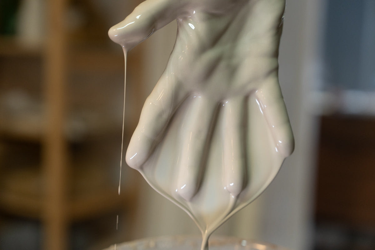 Flüssiges Limoges Porzellan fließt und tropft von einer Hand.