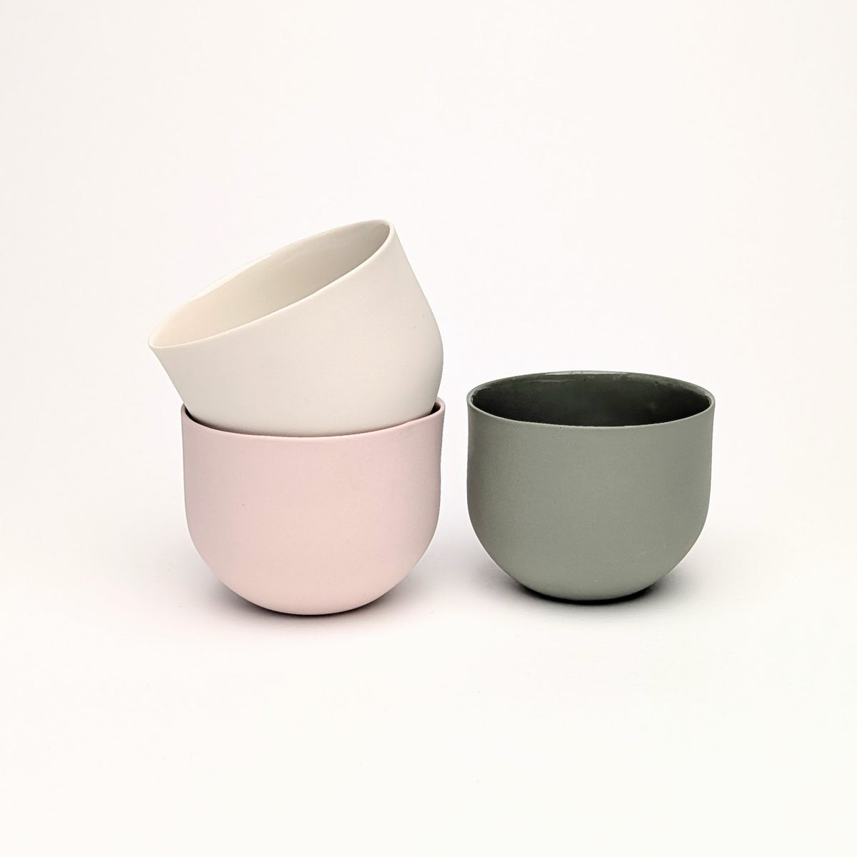 Handgemachte Porzellanbecher in Vintage White, Cotton Candy und Sage von Molekül Ceramics in Berlin.