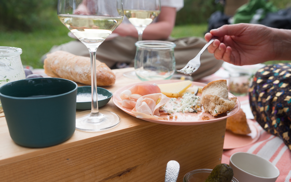 Picknick im Sommer mit handgemachten, grünen Porzellanbechern und orangenen Porzellantellern von Molekül Ceramics.